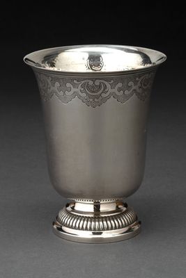 une coupe ancienne en argent posée sur un socle, sur fond noir