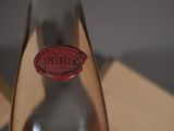 a glass bottle with a red wax stamp on it