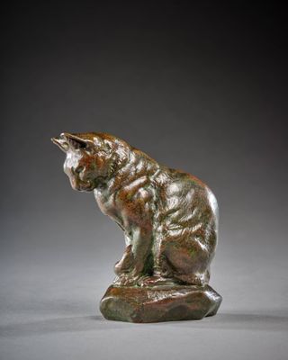 une statue en bronze représentant un chat assis sur un rocher
