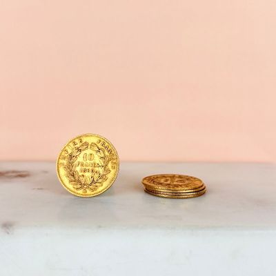 a gold coin sitting next to a stack of gold coins