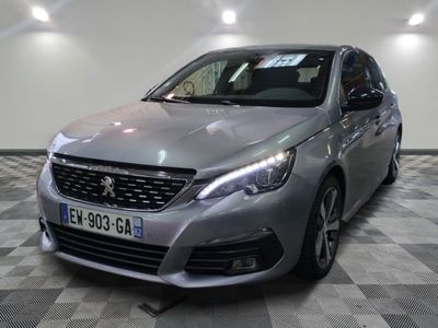 La voiture argentée est garée dans le showroom, sur le sol à damier.