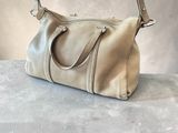 beige leather handbag sitting on a table on a gray surface
