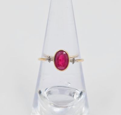 un gros plan d'une bague sertie d'une pierre rouge sur du verre transparent