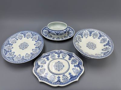 un service composé de quatre assiettes et tasses bleues et blanches