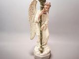 une statue représentant un ange tenant un vase, posée sur un socle