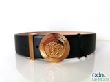 black leather belt with a gold lion buckle on a white surface