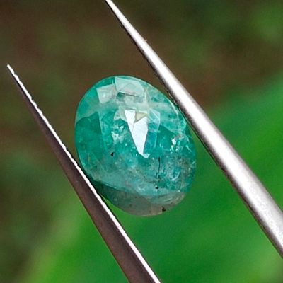 un gros plan d'un diamant vert tenu par une pince