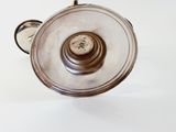 a silver tea pot with a handle on a white table