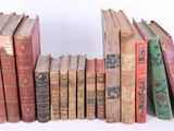 several old books are lined up in a row on a white surface