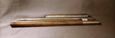 four brass pipes are lined up on a white surface