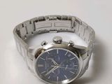 a silver watch with a blue face on a white surface