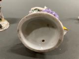 a white vase with a purple flower on it on a table