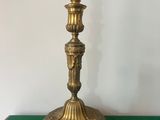 an antique brass candle holder on a green table
