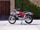 a red and white dirt bike parked in front of a stone building