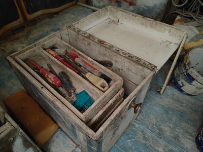 une caisse en bois posée par terre, contenant des outils