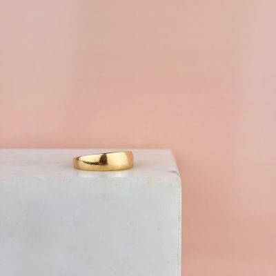 un gros plan d'une bague en or posée sur un bloc blanc