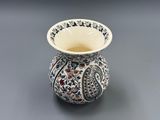 un vase blanc orné d'un motif bleu et rouge