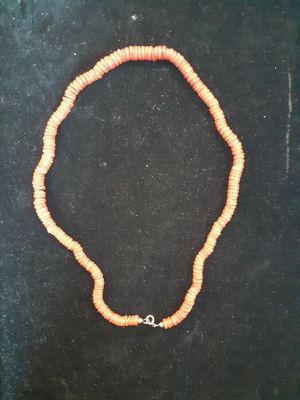 an orange beaded necklace with a silver clasp on a black surface