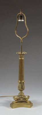 an antique brass table lamp with a black shade on top of it