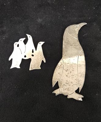 un pingouin en métal argenté et deux pingouins sur fond noir