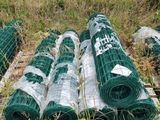 many rolls of green wire on a pallet in the grass