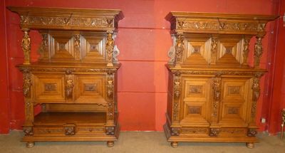 une paire de tables de chevet anciennes en bois sculpté avec des tiroirs, dans une chambre rouge