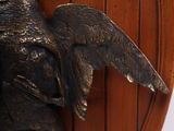 a bronze statue of a bird on a wooden plate