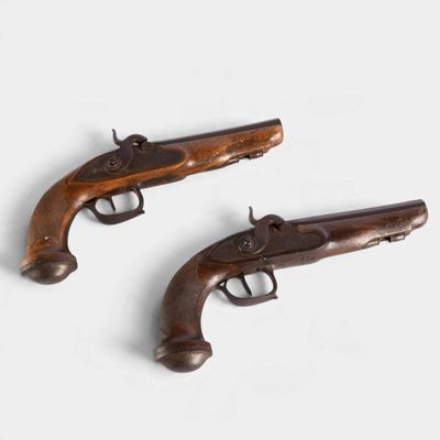 Deux pistolets anciens sont posés sur une surface blanche