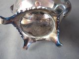 a silver vase with a fish on it on a table