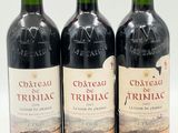 trois bouteilles de vin rouge posées l'une à côté de l'autre sur une surface blanche