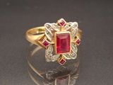 an image of a gold ring with a red stone