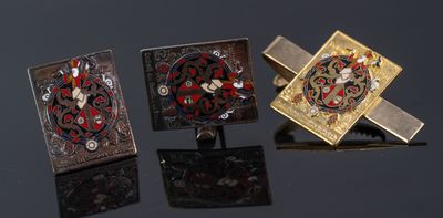three cufflinks of different colors and designs on a black surface