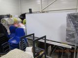 many chairs and tables in a warehouse with a white board