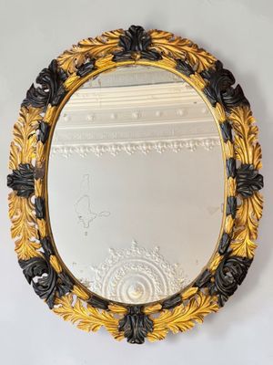 an ornate gold and black mirror hanging on a wall