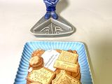 une assiette bleue sur laquelle sont posés des biscuits, à côté d'une assiette bleue sur laquelle se trouve une petite figurine représentant un homme
