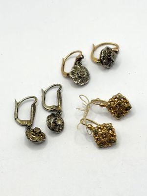 trois paires de boucles d'oreilles et une paire de boucles d'oreilles posées sur une surface blanche