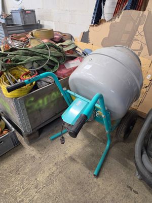 une bétonnière dans un garage, à côté d'un tas d'autres objets