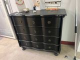 une commode noire dans une pièce où un miroir est accroché au mur