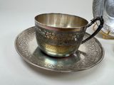 a silver cup and saucer sitting on a table