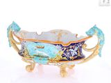 a blue and gold bowl on a stand on a white surface