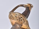 a gold sword with a wooden handle on a white surface