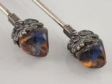 pair of silver and amber glass acorns with leaves and leaves on them