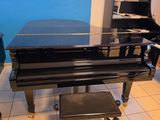 un piano noir posé dans une pièce aux murs bleus