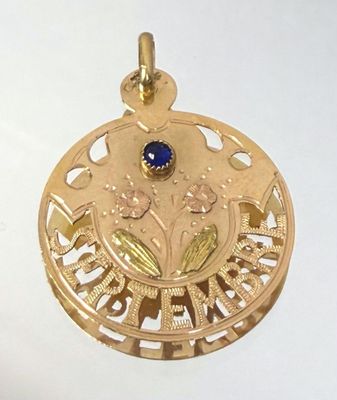 a gold pendant with a blue stone in the center