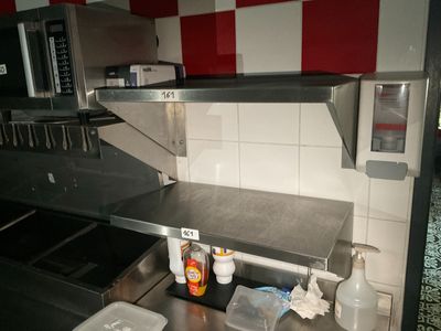 plan de travail en acier inoxydable dans une cuisine professionnelle aux murs à carreaux rouges et blancs