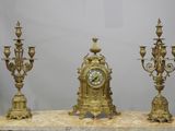 three gold colored clocks sitting on top of a marble table