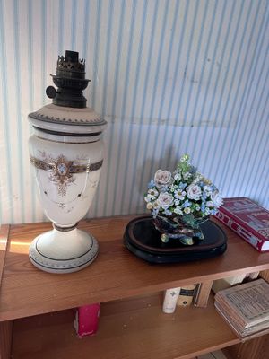 a white vase sitting on top of a wooden shelf next to a book shelf
