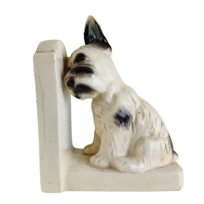 statue d'un chien assis au sommet d'une bibliothèque blanche