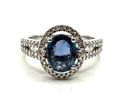 gros plan d'une bague avec une pierre bleue entourée de diamants blancs