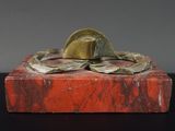 statue d'un homme coiffé d'un chapeau, posée sur un bloc de marbre rouge
